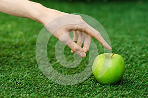 Vegetarians and fresh fruit and vegetables on the nature of the theme: human hand holding a green apple on a background of green g