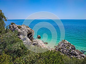Vegetation and rocks with clear turquoise water from the Atlantic Ocean at Galapos beach, ArrÃÂ¡bida - SetÃÂºbal PORTUGAL photo