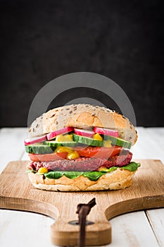 Veggie beet burger on a white wooden table and black background