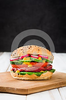 Veggie beet burger on a white wooden table and black background