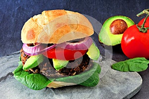 Veggie burger with avocado and spinach on a dark background