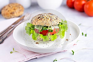 Veggie burger with tomato, ettuce and micro grins on a white plate with tomatoes, cereal bun on a white background