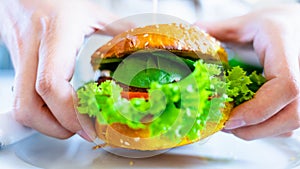 Veggie sandwich healthy vegan burger. Cute cheerful girl eating vegetarian hamburger with salad, avocado, vegetable