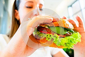 Veggie sandwich healthy vegan burger. Cute cheerful girl eating vegetarian hamburger with salad, avocado, vegetable