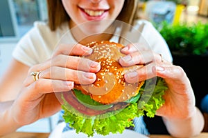 Veggie sandwich healthy vegan burger. Cute cheerful girl eating vegetarian hamburger with salad, avocado, vegetable