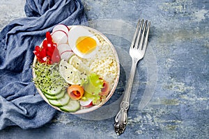 Veggies detox Buddha bowl recipe with egg, carrots, sprouts, couscous, cucumber, radishes, seeds. Top view, flat lay, copy space