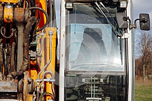 Vehicle cockpit of excavator, yellow metallic structure with transparent windshield