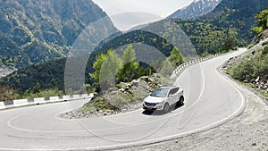Vehicle crosses mountainous terrain on winding asphalt road
