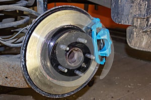 Vehicle disc brake for repair, in the process of replacing new tires. Repair of car brakes in the garage.