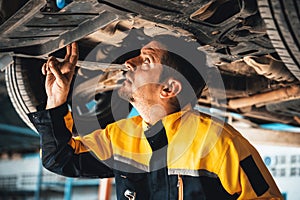 Vehicle mechanic conduct car inspection from beneath lifted vehicle. Oxus