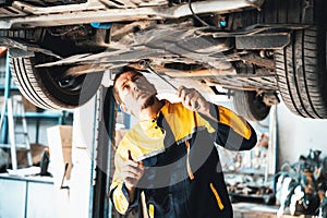 Vehicle mechanic conduct car inspection from beneath lifted vehicle. Oxus