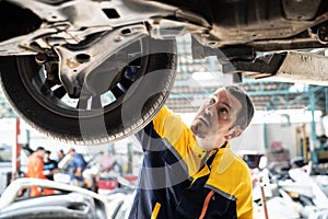 Vehicle mechanic conduct car inspection from beneath lifted vehicle. Oxus