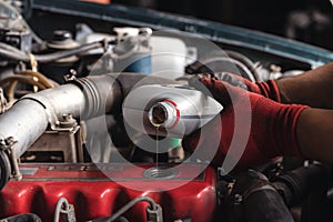 Vehicle mechanic filling oil lubricant into engine of car during routine service maintenance