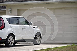 Vehicle parked in front of wide garage double door on paved driveway of typical contemporary american home