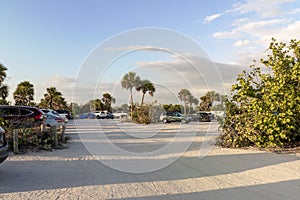 Vehicle parking area with cars parked on ocean beach parking lot at sunset. Summer vacation on beachfront in Southern