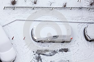 Vehicle standing at winter parking place, working engine car covering with snow, top view