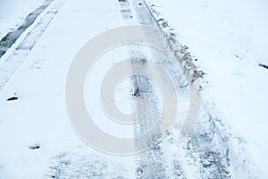 Vehicle tire tracks on road covered in snow and ice. Winter driving conditions