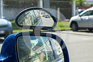 A vehicles blue car reflected in an automotive sideview mirror