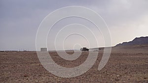 Vehicles on Desert Road Moving in a Dust, Wide View