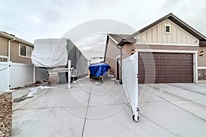 Vehicles at an open parking area beside attached home garage with brown door