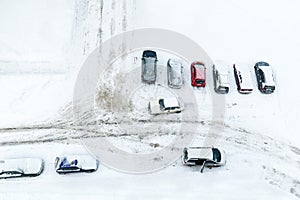 Vehicles standing at winter parking lot covering with snow. Top view