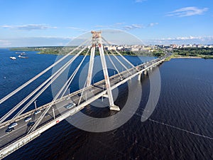 Vehicular cable-stayed bridge with vehicle flows on road lanes. Aerial view at the riverbank and part of carriageway. Cherepovets,