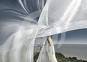 Veil of beautiful bride on a cliff above the sea