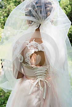 Veil makes a hat on bride`s head while she holds her hands on back