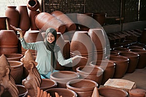 veiled woman with hand gestures offering something between the pottery