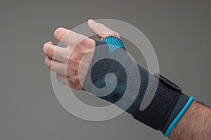 Velcro wrist stabilizer cast worn by Caucasian male hand. A blue split brace meant to aid Carpel Tunnel syndrome. Close up studio