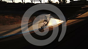 Velodrome cyclist rotates in an empty stadium, light and shadow - 4K