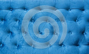 Velour surface of sofa close-up. Coach-type velours screed tightened with buttons. Blue chesterfield style quilted