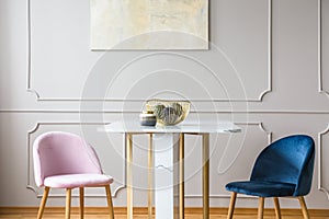 Velvet pastel pink and petrol blue chairs at small dining table in living room