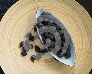 Velvet tamarind fruit  Dialium cochinchinense or buah keranji in a wooden bamboo plate background