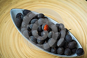 Velvet tamarind fruit  Dialium cochinchinense or buah keranji in a wooden bamboo plate background