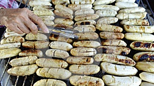 Vender's hand grilling banana on grille. photo