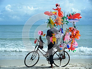 venditore di giocattoli in spiaggia con bicicletta