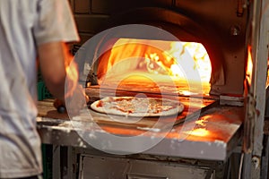 vendor baking pizza in mobile woodfired oven