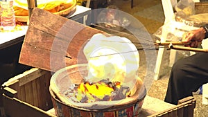 A vendor grills kite crackers on a charcoal grill.