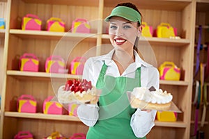 Vendor in pastry shop hold two nice cakes in hands