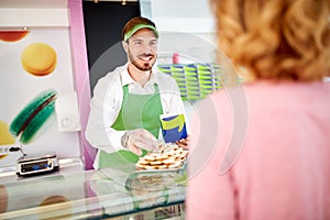 Vendor in pastry shop selling sweets to costumer