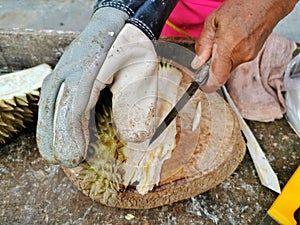 The vendor peeled the durian hard, thick and with sharp spikes.