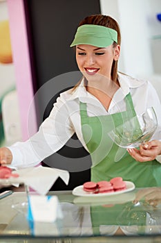 Vendor putting macaronis on plate in pastry store