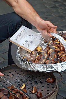 Vendor in Rome offering roasted chestnuts to tourists