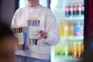 A vendor stands outside the cinema, holding freshly popped popcorn to sell to moviegoers before they enter the theater photo