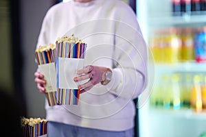 A vendor stands outside the cinema, holding freshly popped popcorn to sell to moviegoers before they enter the theater photo