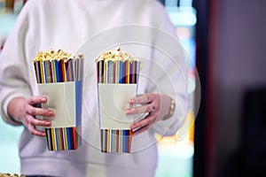 A vendor stands outside the cinema, holding freshly popped popcorn to sell to moviegoers before they enter the theater photo