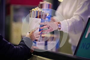 A vendor stands outside the cinema, holding freshly popped popcorn to sell to moviegoers before they enter the theater photo