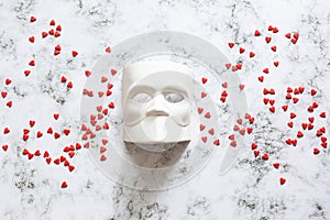 Venetian Bauta mask, Casanova mask on a marble background with confetti hearts. Concept - Venetian carnival masquerade, festival,