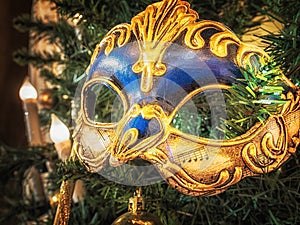 Venetian carnival mask on christmas tree. Christmas and New Year`s background. Christmas tree, ball, candle, mask